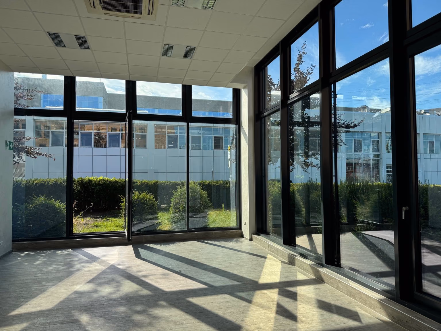 Tagungsraum im Erdgeschoss des COWORX Paderborn: heller Eckraum mit raumhohen Fensterfronten zur begrünten Außenfläche, aktueller Zustand vor der Einrichtung